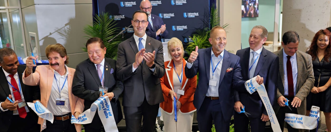 Several people are gathered, cutting a ribbon together at a ceremonial event, marking a significant occasion