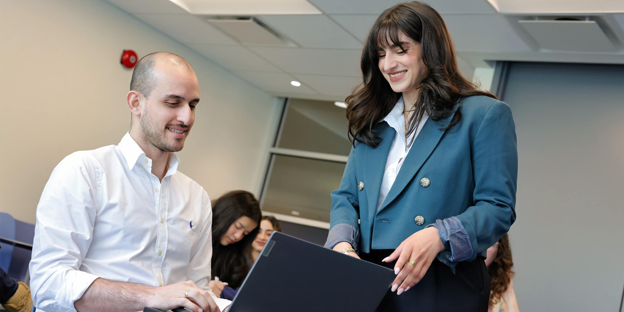 A woman instructs a male student in a classroom setting
