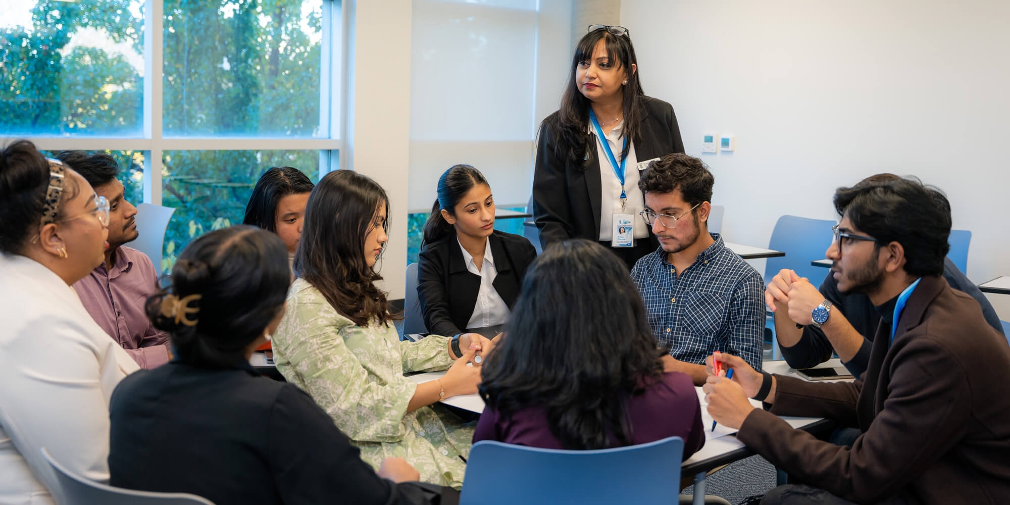 A classroom scene featuring a group of people gathered around a table, engaged in collaborative learning