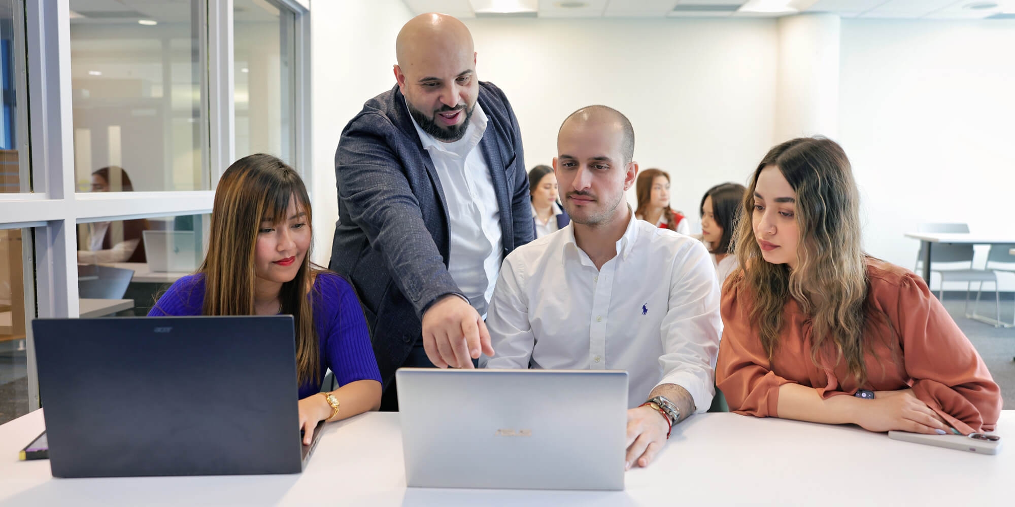 Team members focused on their laptops, engaged in work within a contemporary office setting