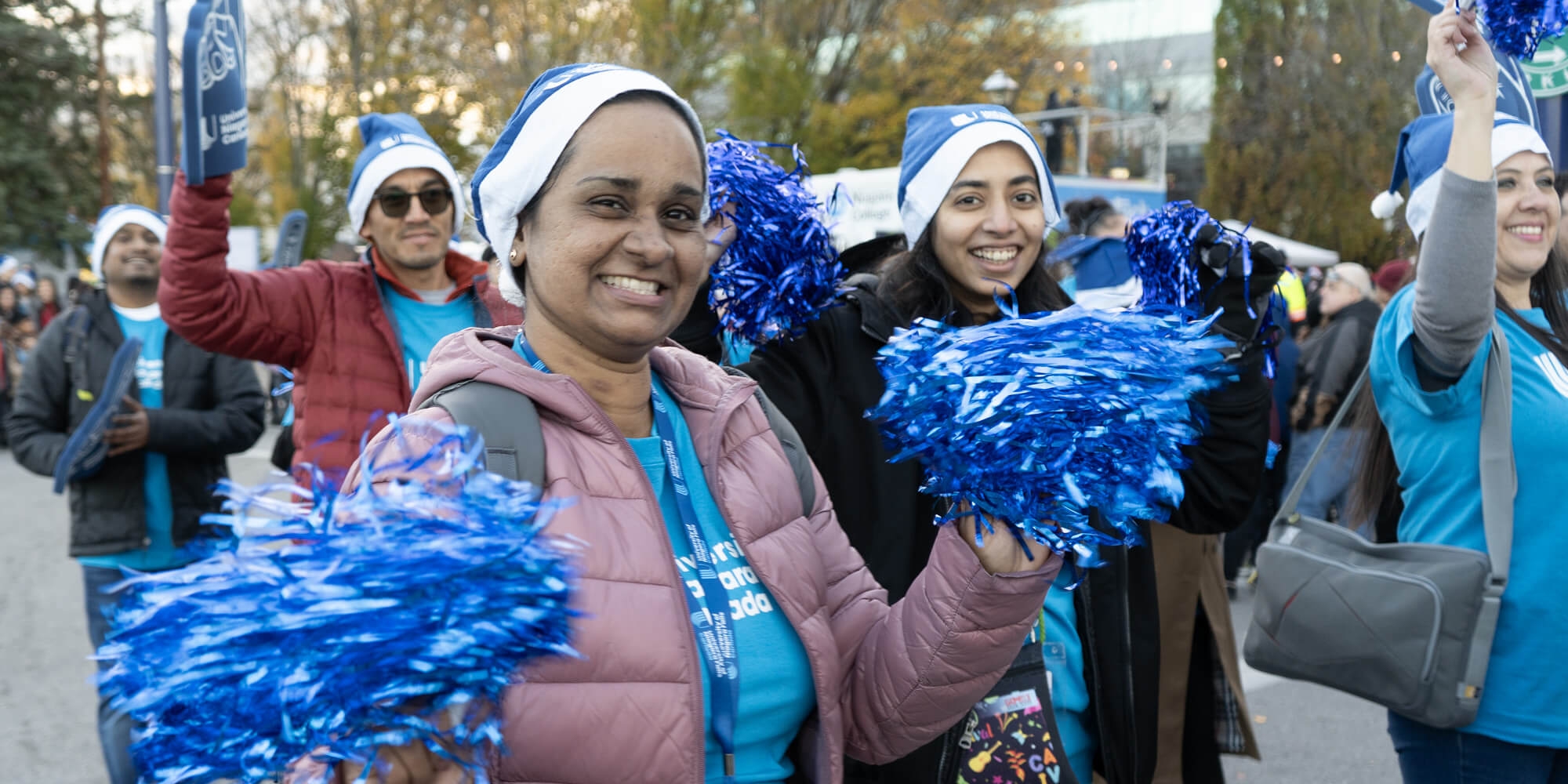 A lively group of individuals in blue cheerleading outfits, proudly displaying pom poms and celebrating their team spirit