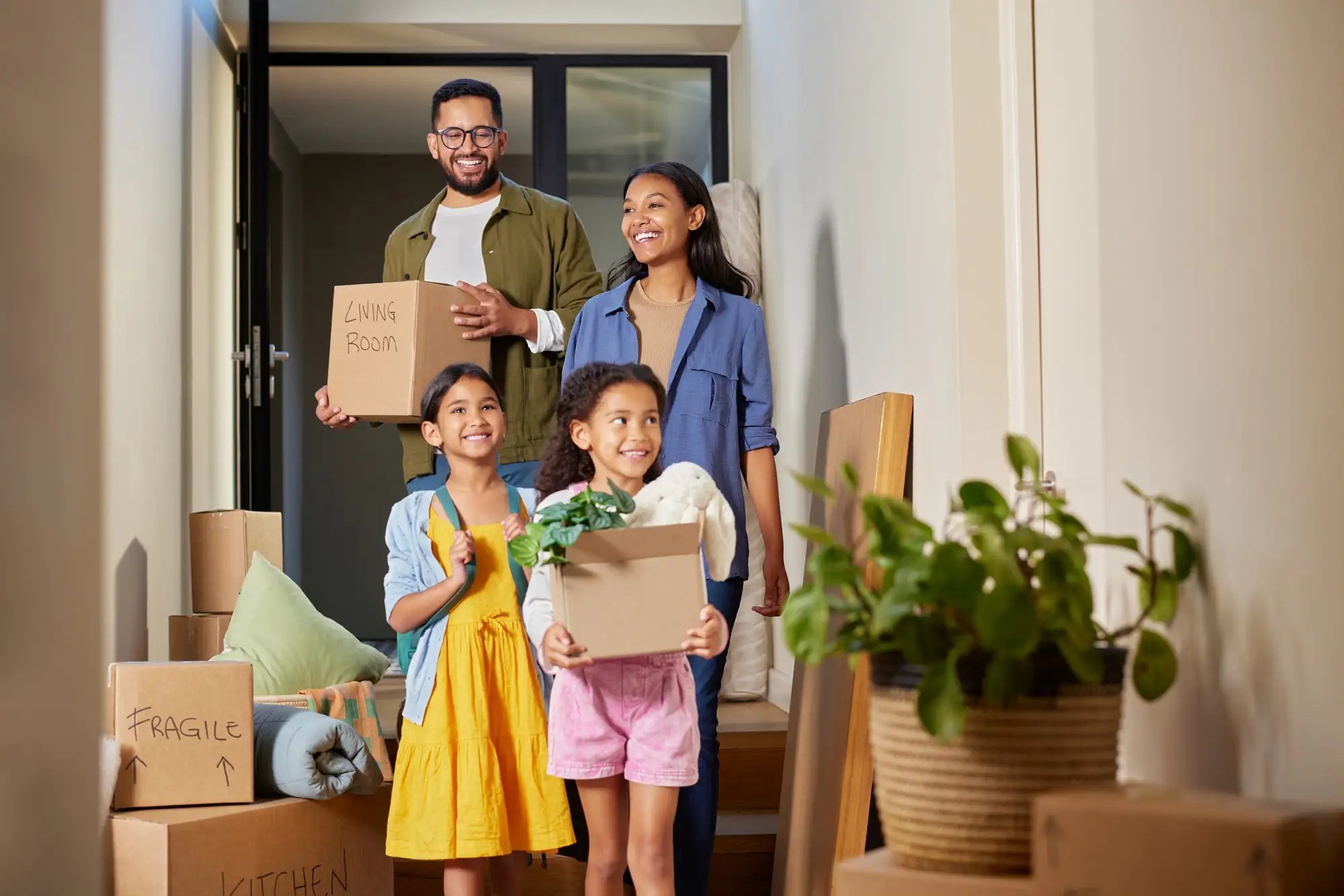 A small family moving in to a new house carrying boxes and things