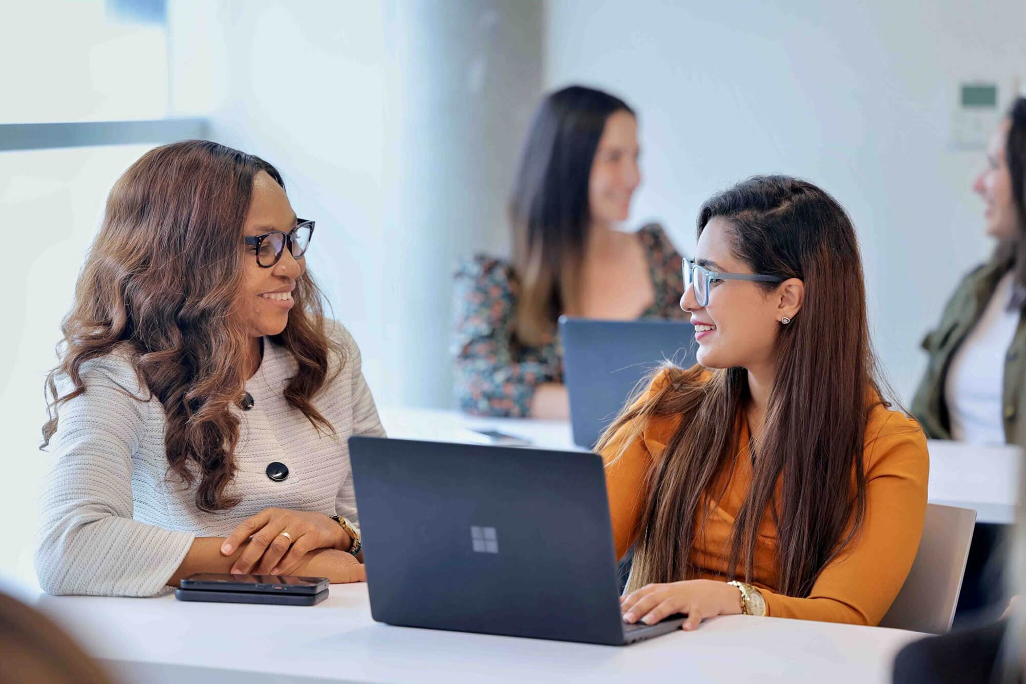 Two women having a cheerful conversation in front of a laptop