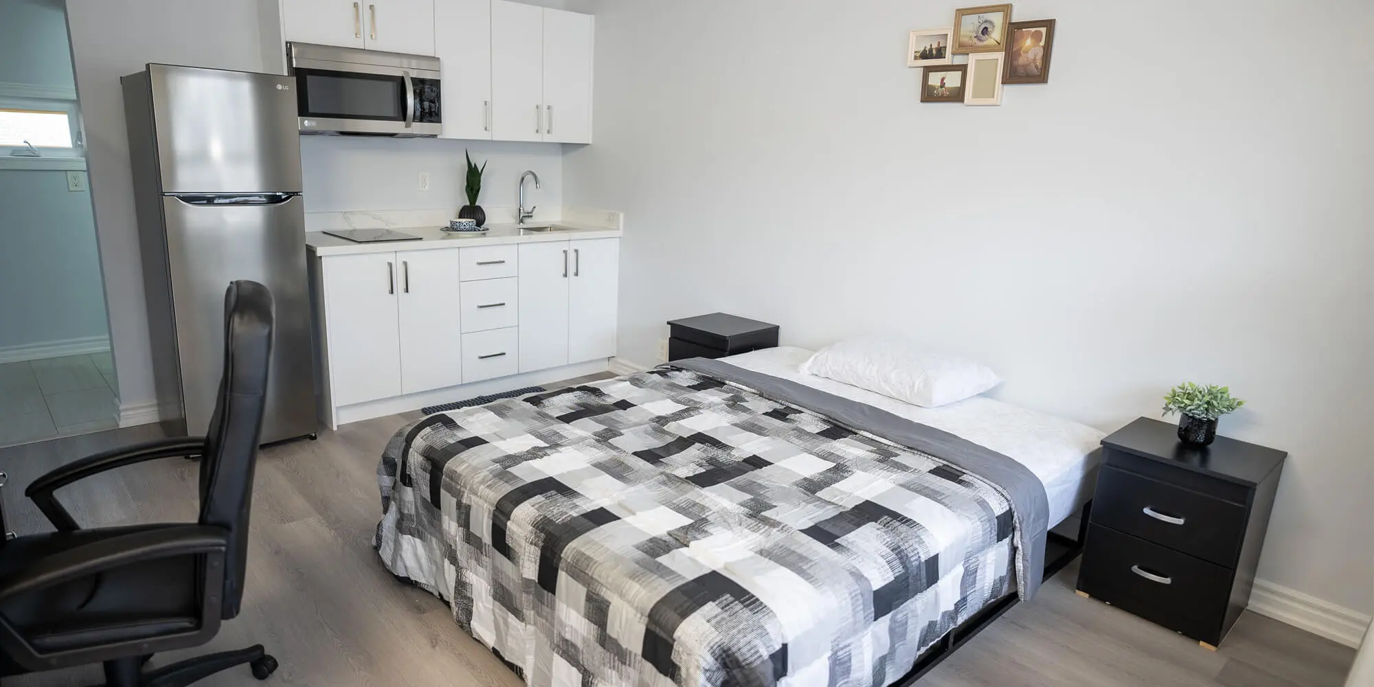 A small bedroom featuring a bed, a desk, and a refrigerator, creating a cozy and functional living space