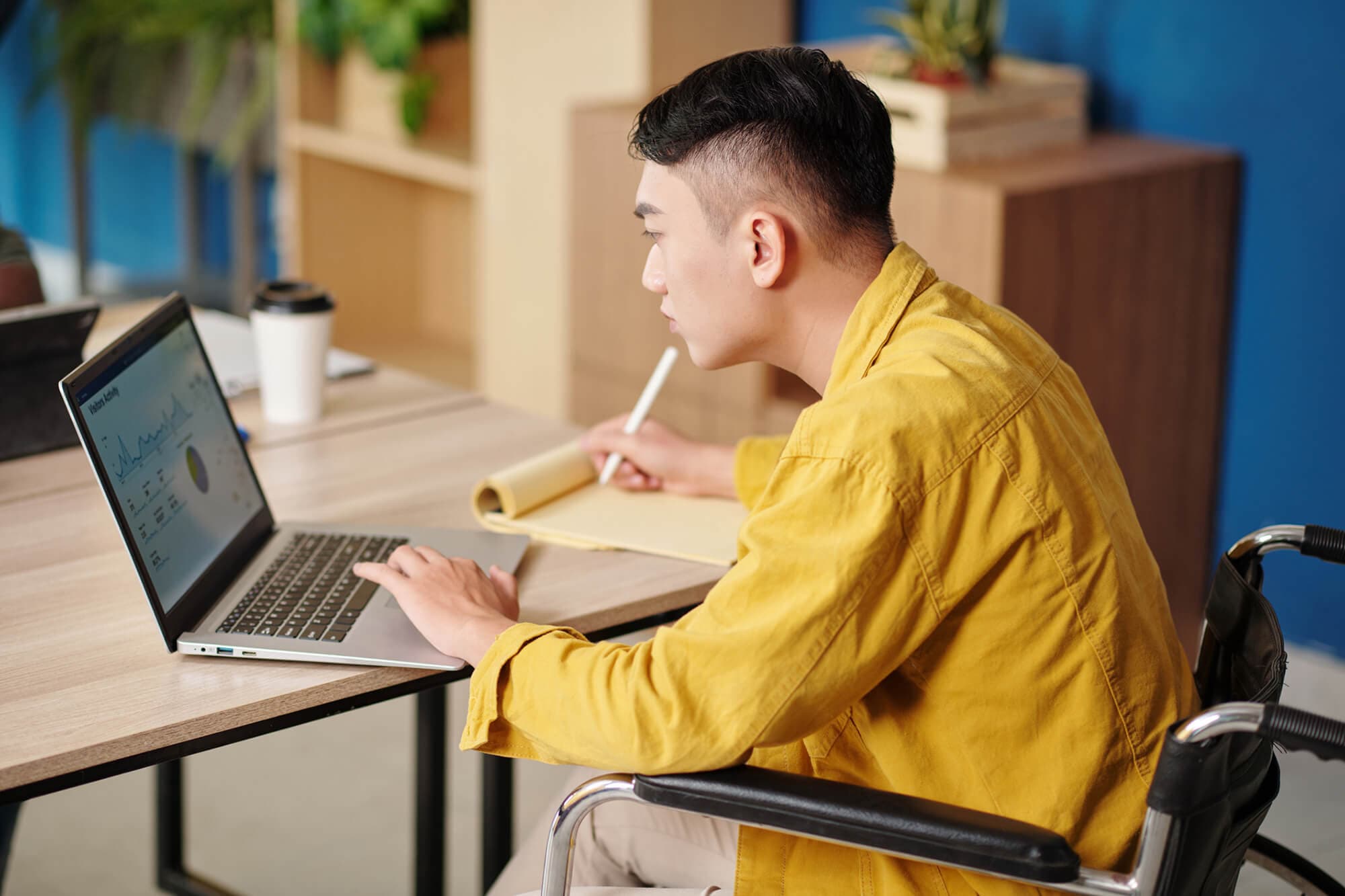A man in a wheelchair utilizes a laptop, demonstrating the importance of accessibility in modern technology