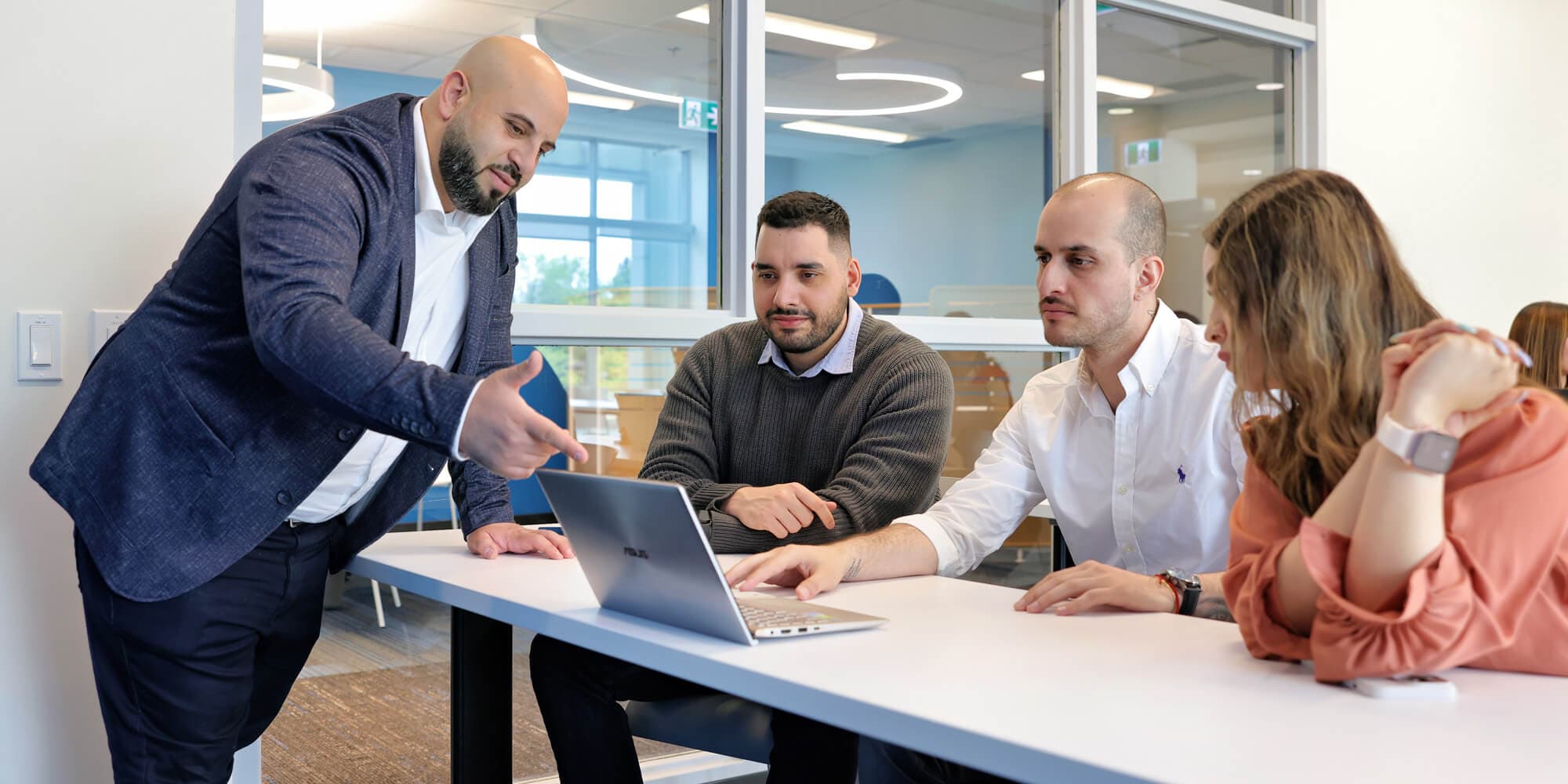 Team members focused on a laptop, engaged in work within a contemporary office setting