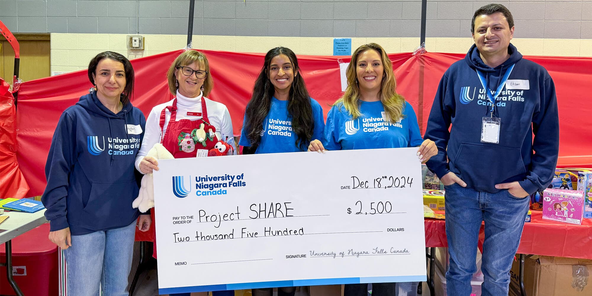 A group of individuals proudly holding a large check worth two thousand five hundred dollars, celebrating a significant achievement together