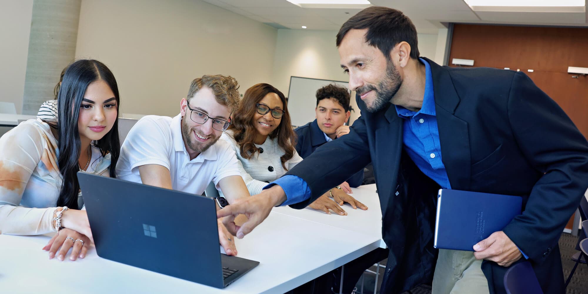 A group of students with a laptop showing something to their professor
