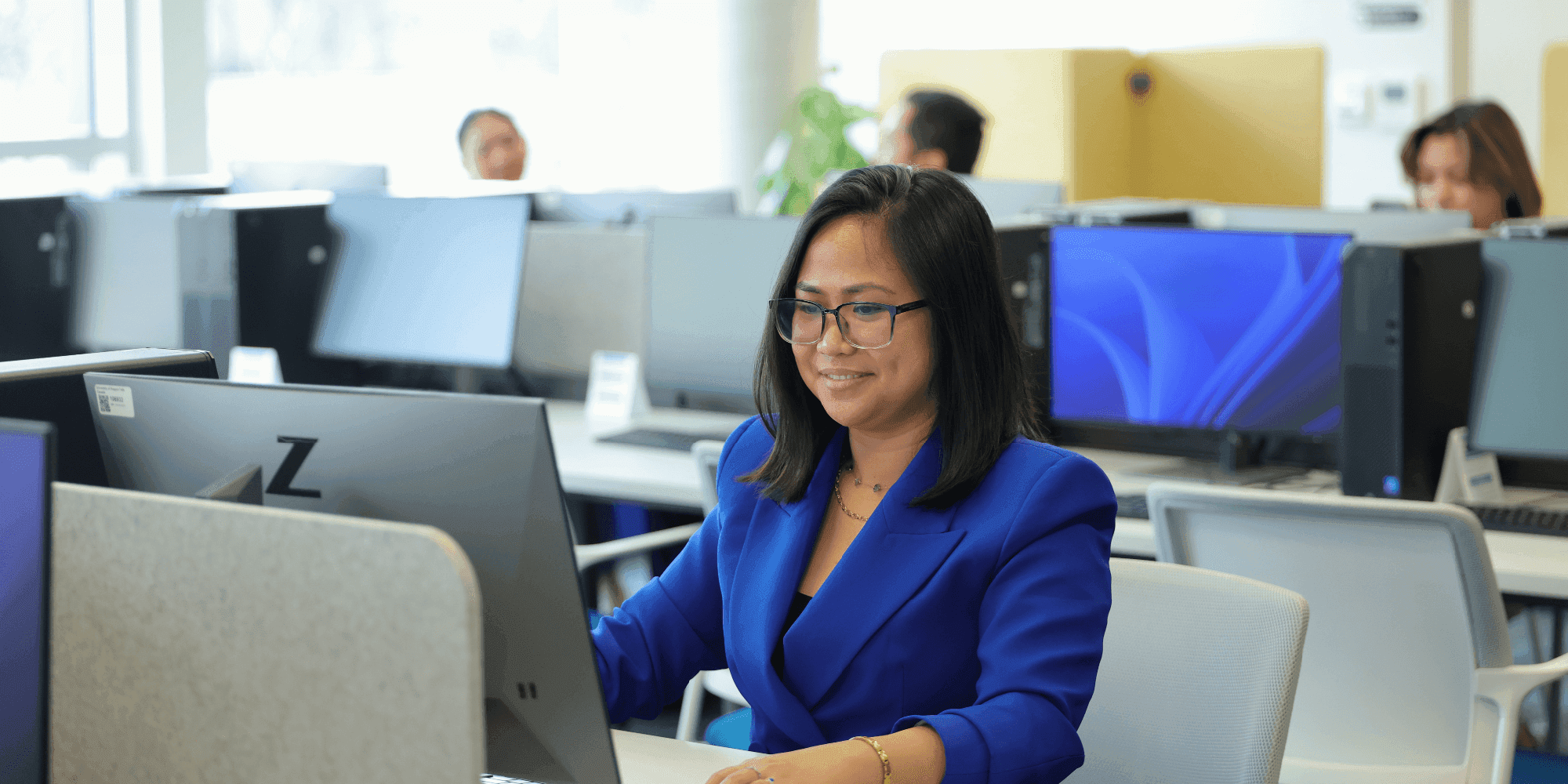 A woman smiling in front of a desktop computer