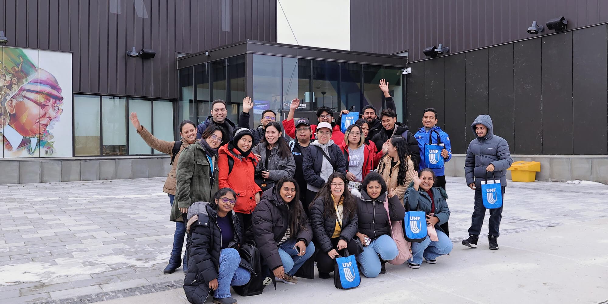 A diverse group of individuals smiling and posing together in front of a large building