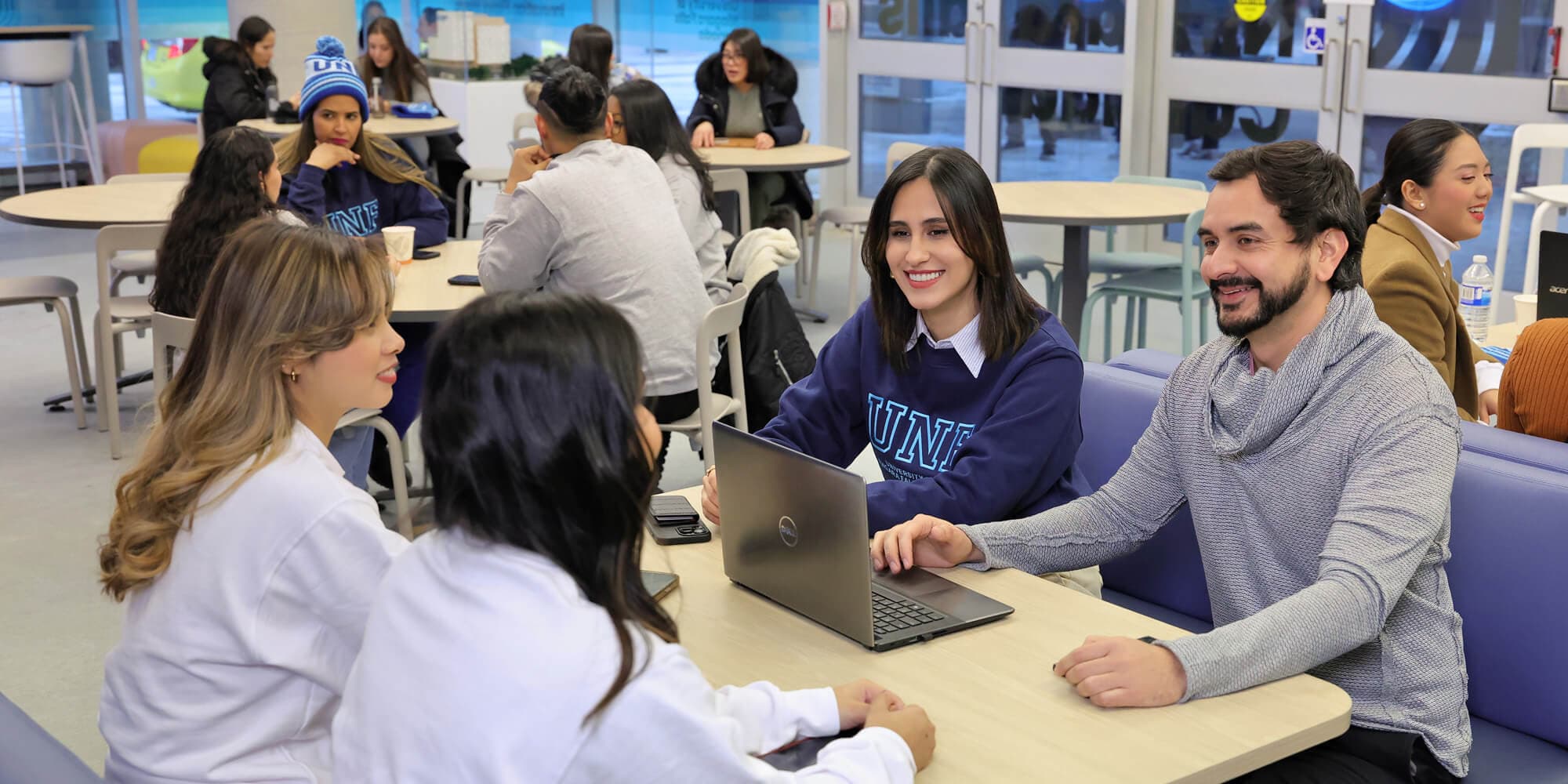 A diverse group of individuals with a laptop engaged in a discussion inside UNFC campus