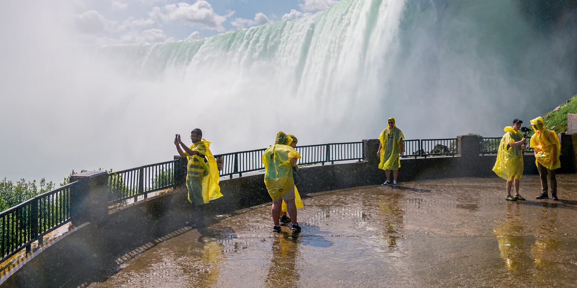 A scenic view of Niagara Falls featuring people in rain coats set against the majestic waterfall backdrop