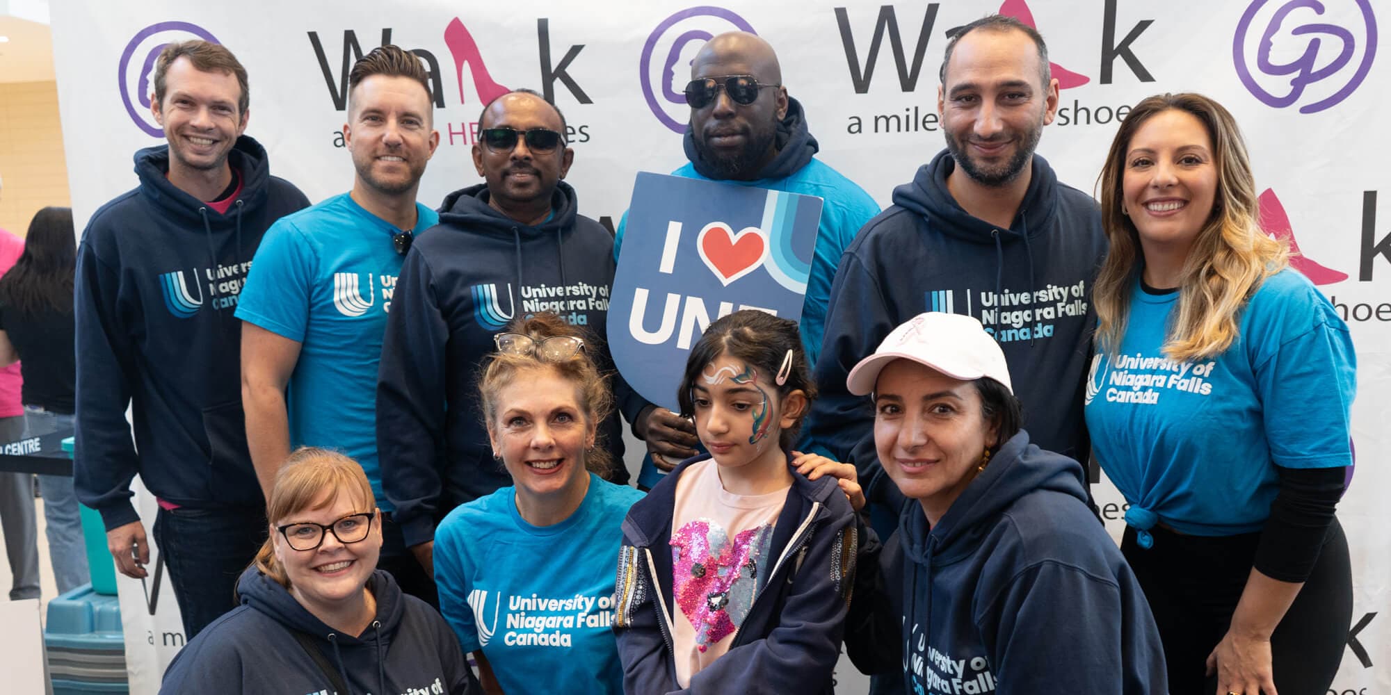 A diverse group of individuals wearing blue shirts, gathered together in a cheerful setting