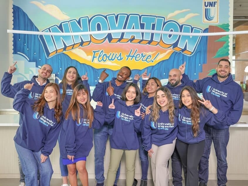 A team of individuals seated at a table in an office all smiling for the camera