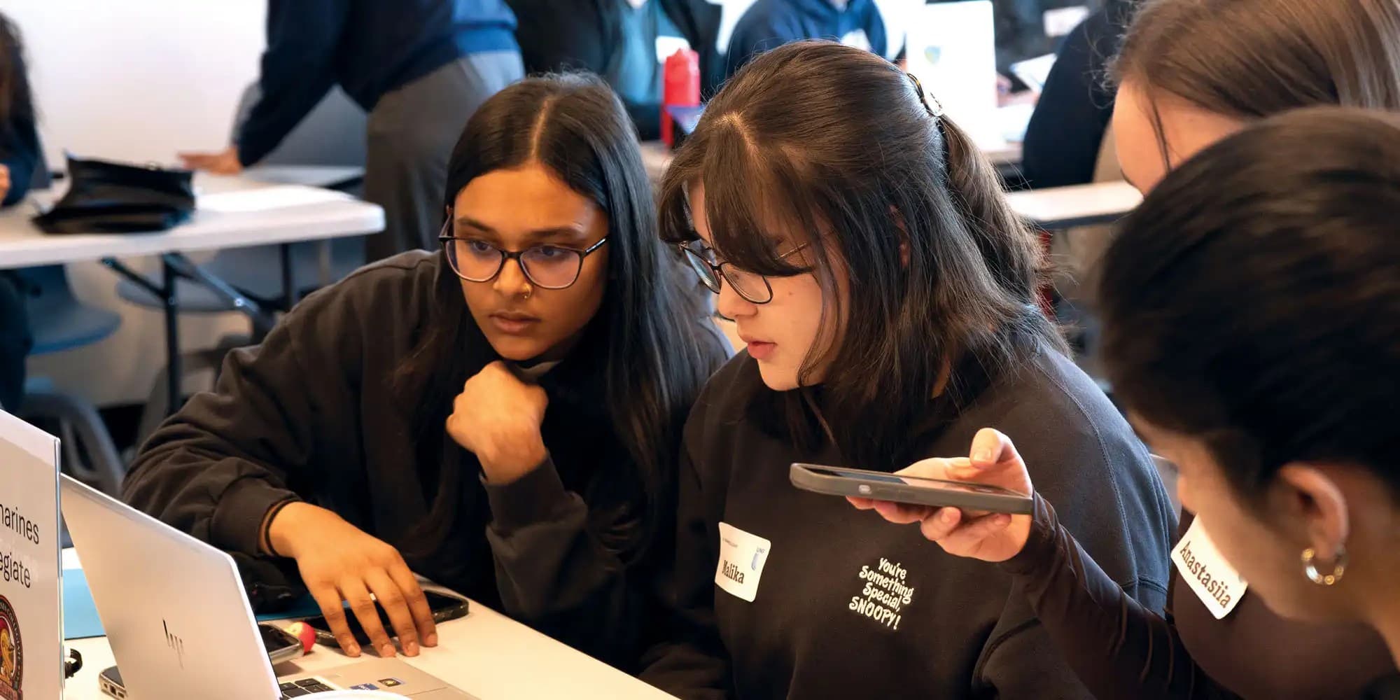 UNF students looking at laptop screen and pointing at it