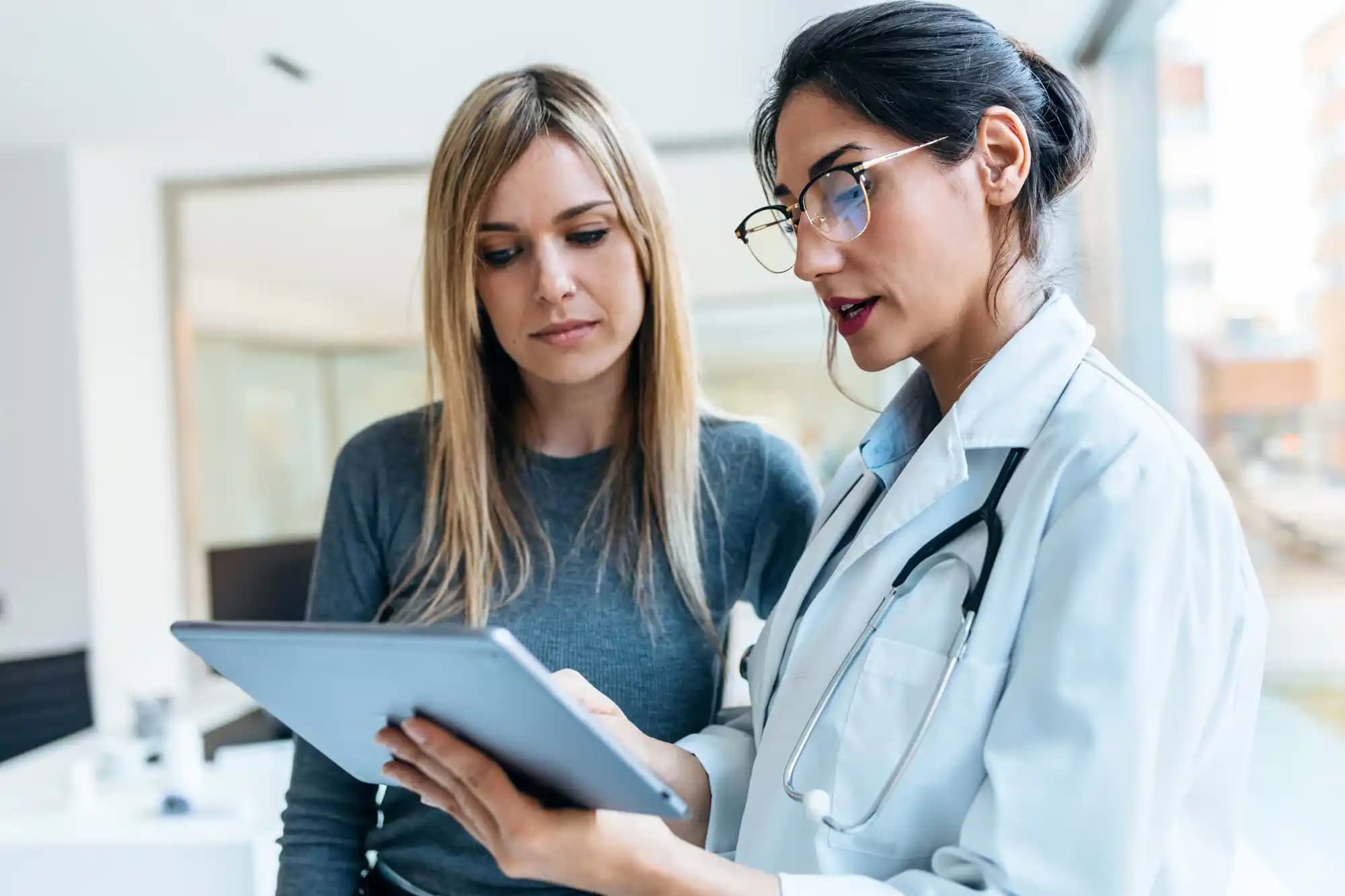 A doctor pointing at a tablet and another women looking at the screen