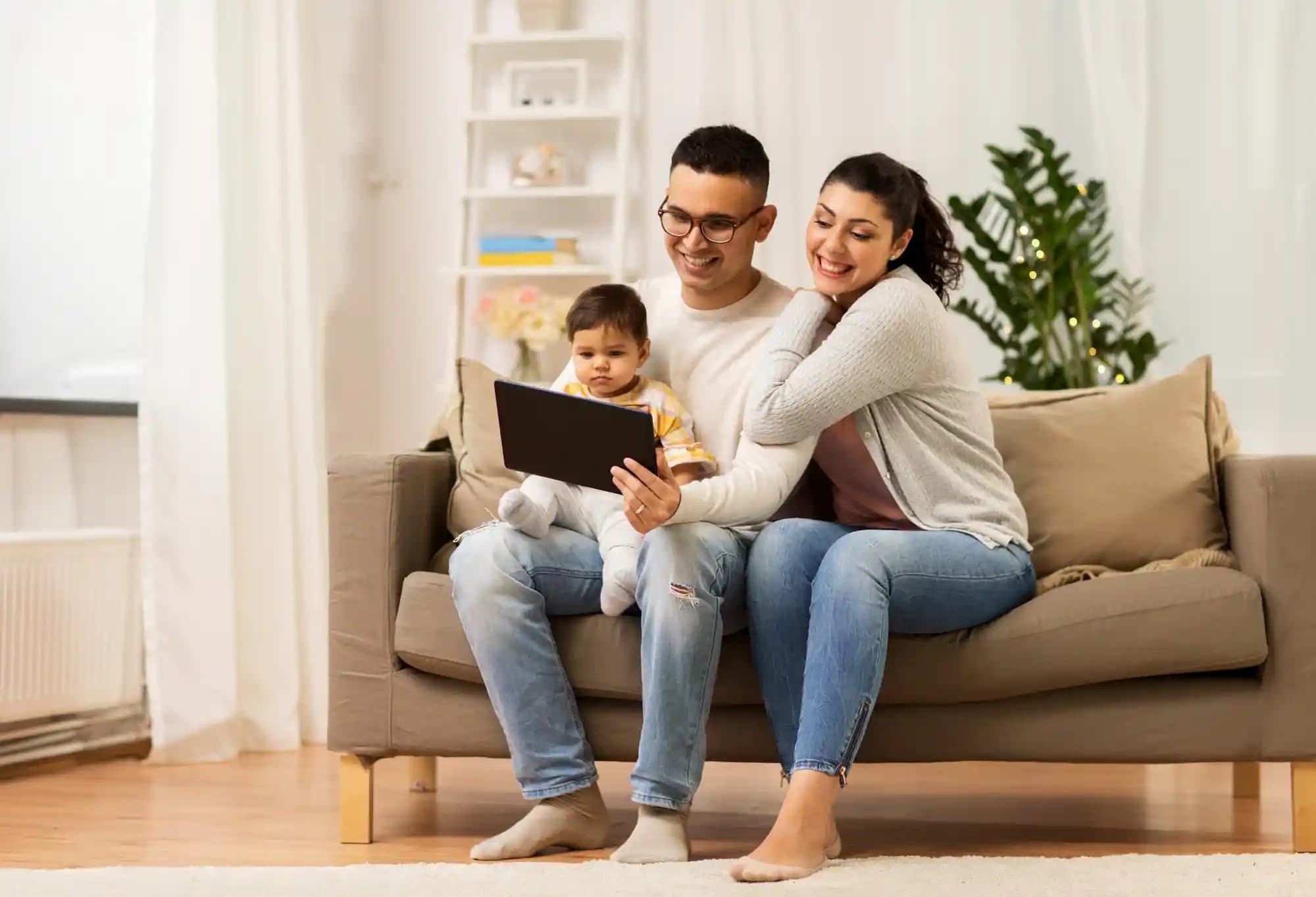 A family of three looking at a tablet screen and smiling