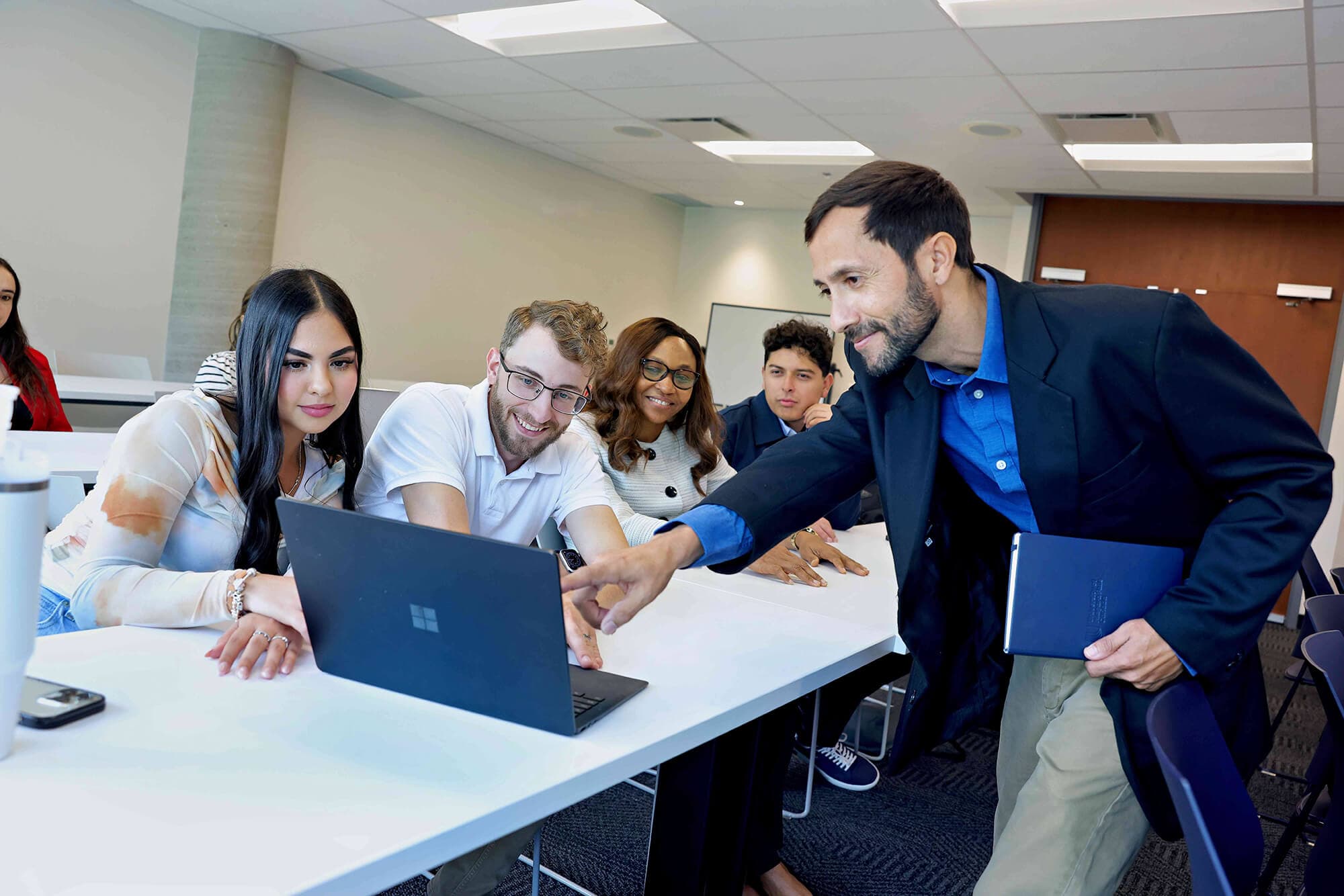 A group of students with a laptop showing something to their professor