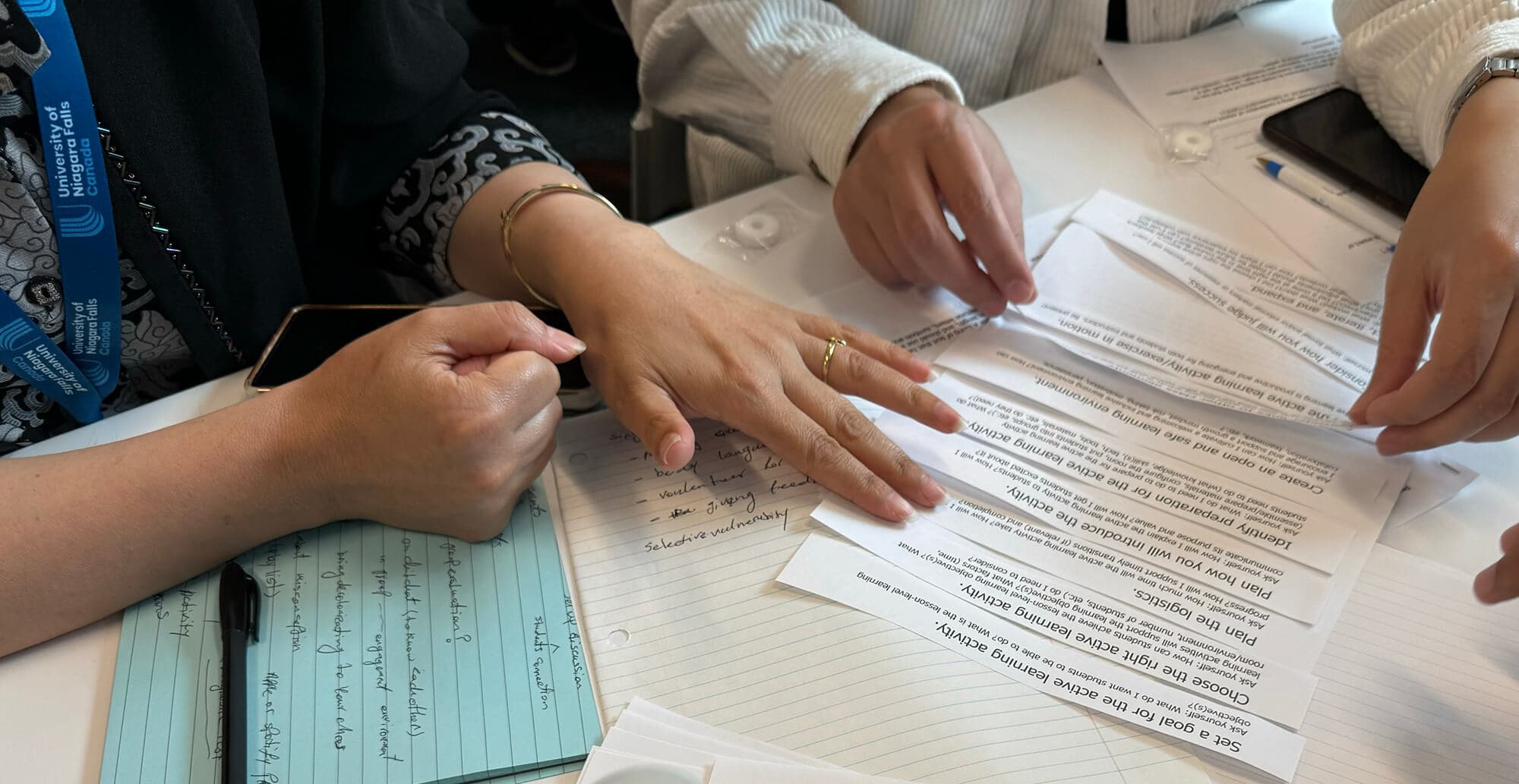 A diverse group of individuals gathered around a table, engaged in discussion with papers spread out before them