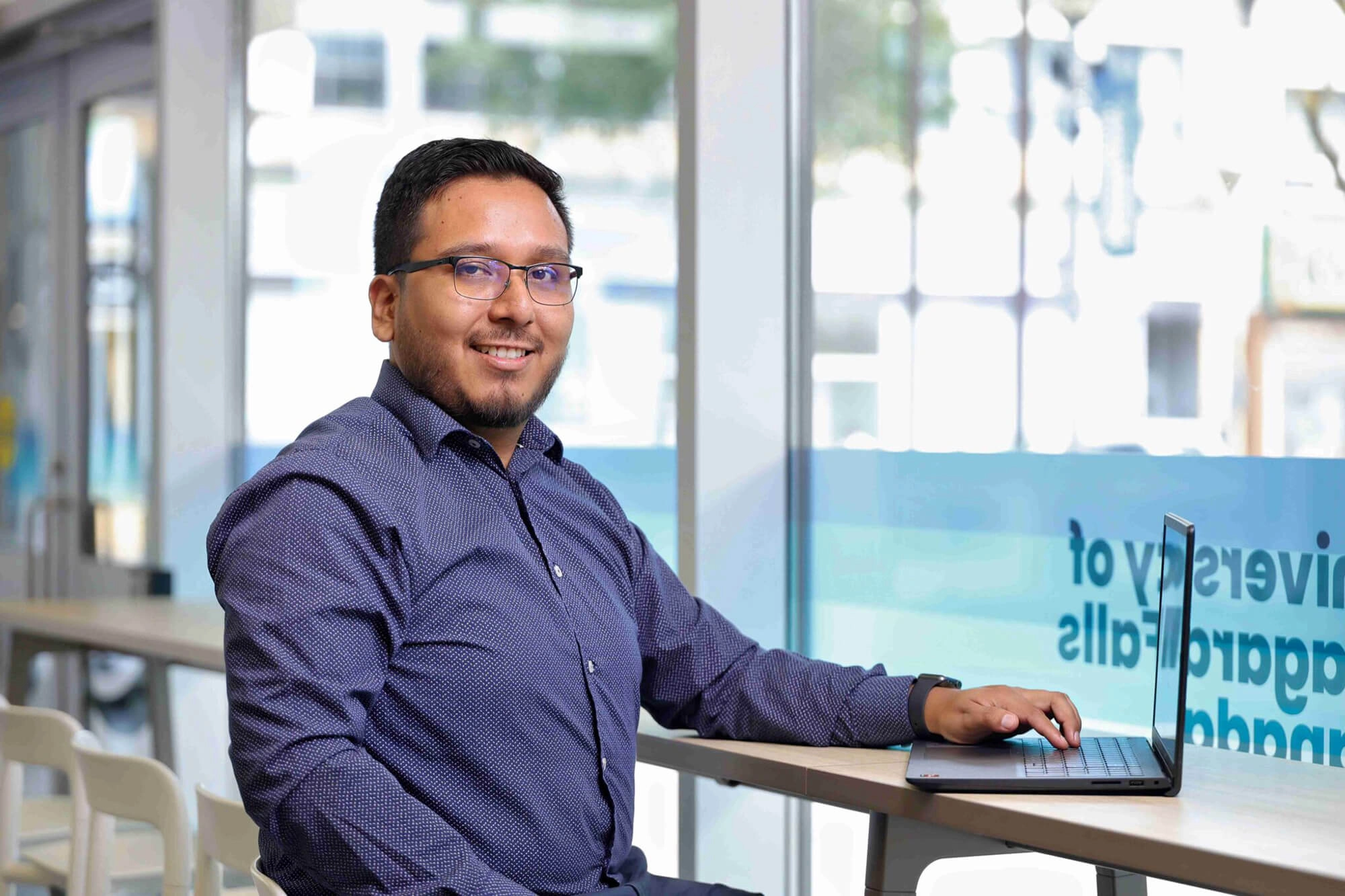 A man with a laptop smiling for the camera