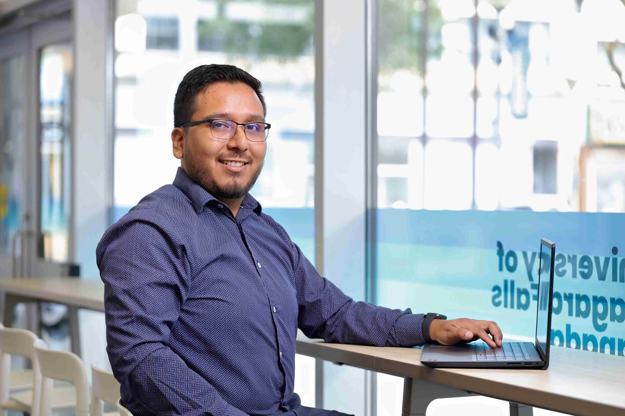 A man with a laptop smiling for the camera