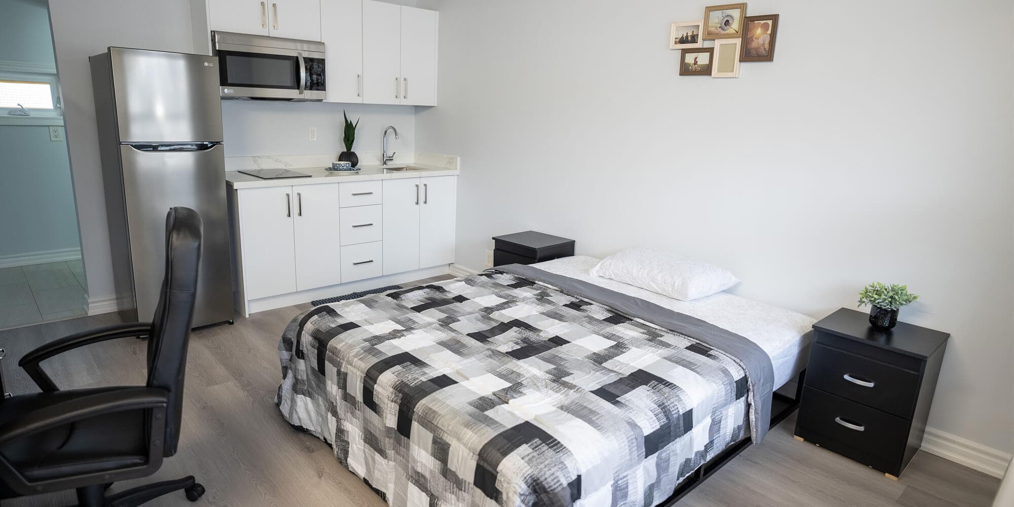 A small bedroom featuring a bed, a desk, and a refrigerator, creating a cozy and functional living space