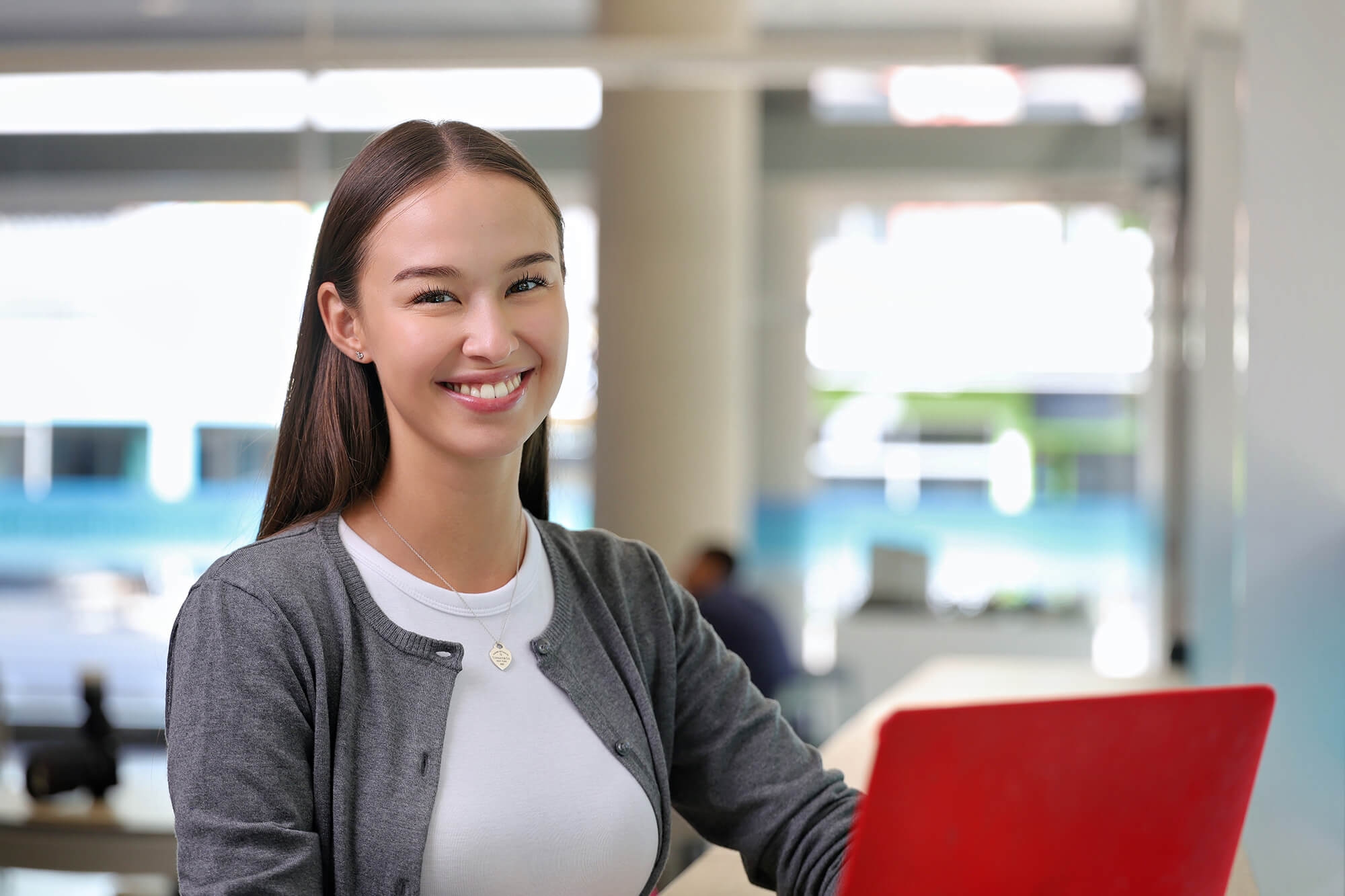 A female student with a laptop smiling for the camera