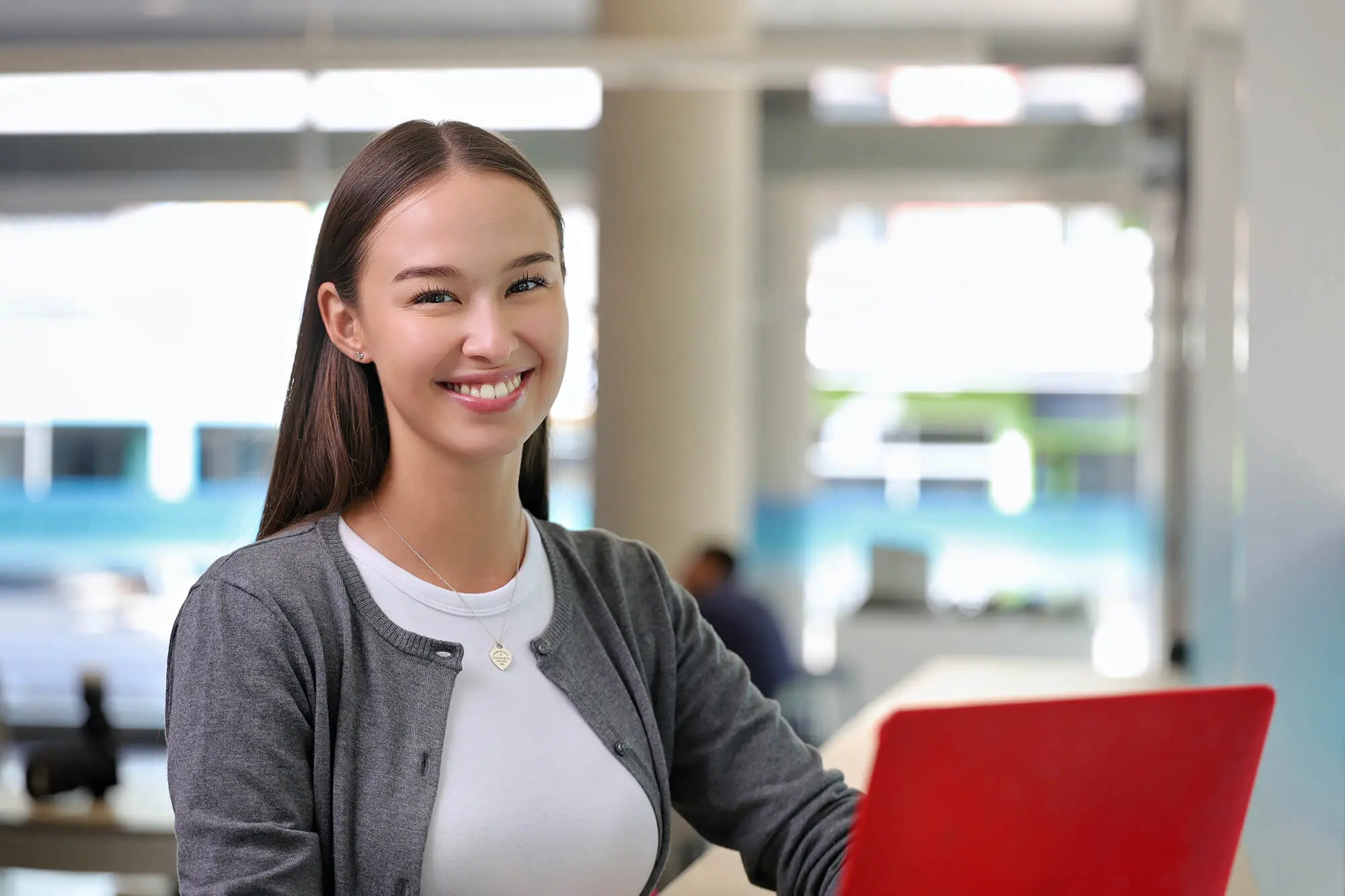 A female student with a laptop smiling for the camera