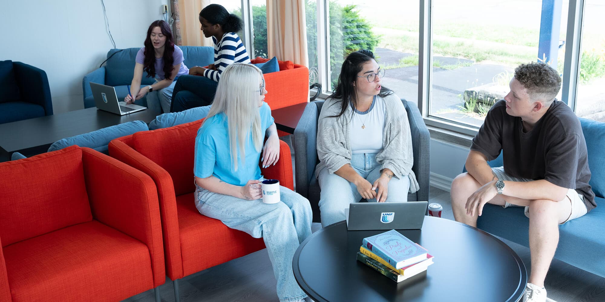 A group of three students with a laptop talking to each other in a relax environment inside UNFC campus