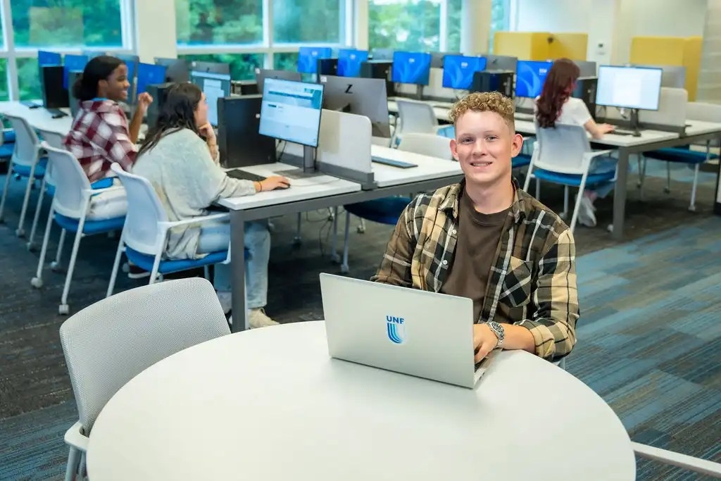 A UNF student sitting inside the university computer lab and posing for a picture