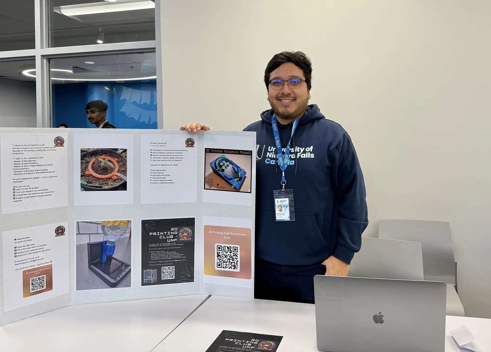 A UNF student from 3D Printing Club holding a presentation board