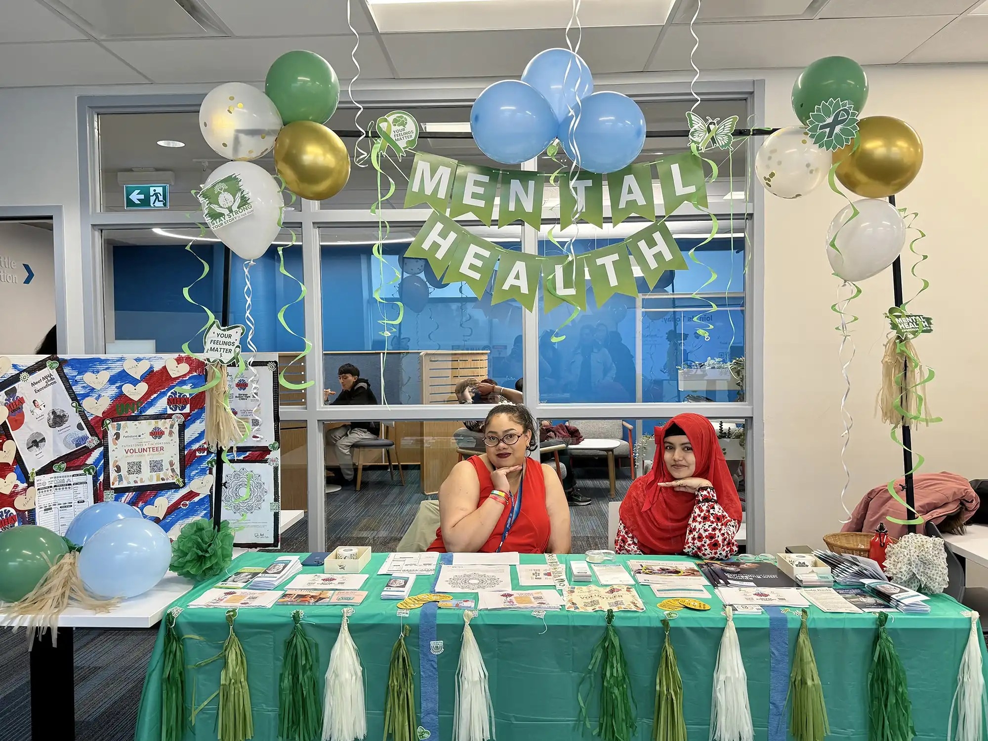 Two female students sitting at the mental health association booth