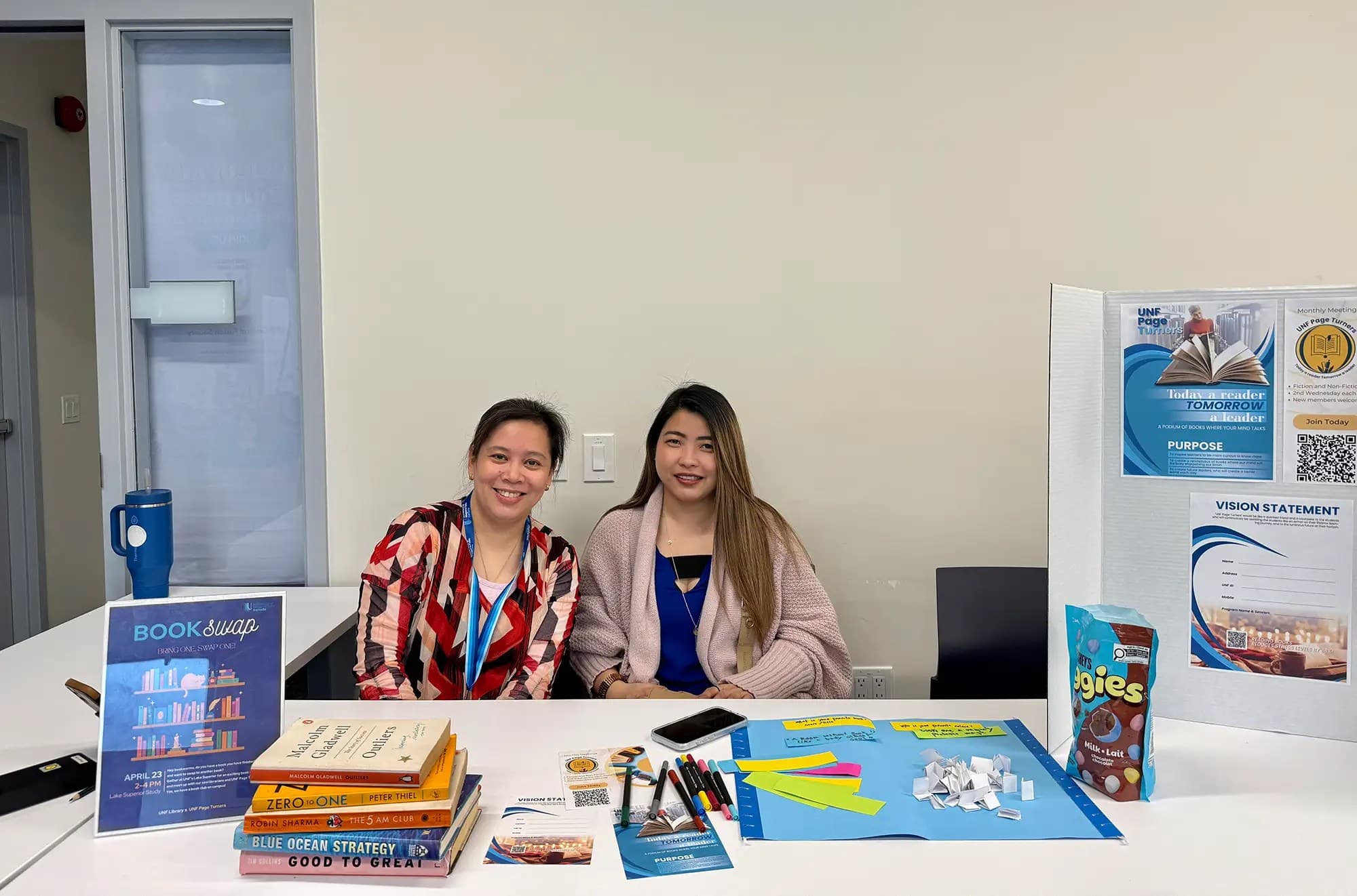 UNF students from UNF Page Turners club sitting at a booth table