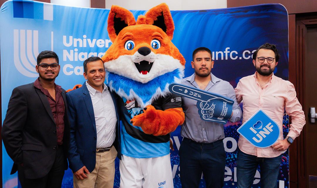 Spark posing for a picture with a UNF staff and students