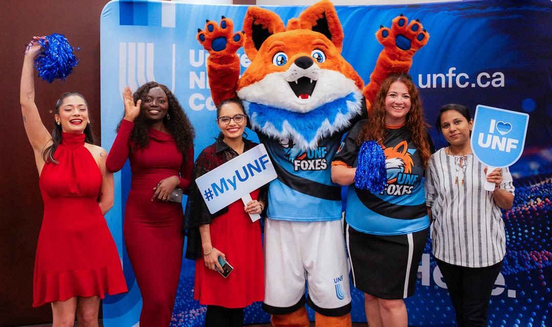Spark posing for a picture with a UNF staff and students