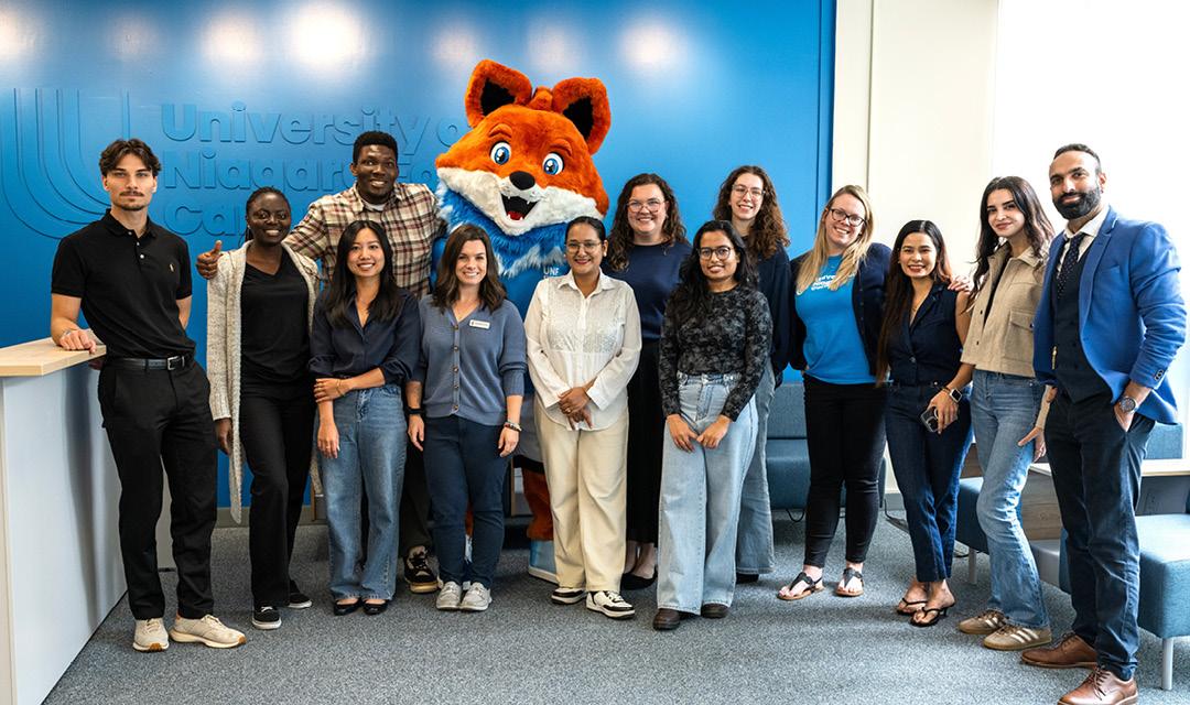 Spark posing for a picture with a UNF staff and students
