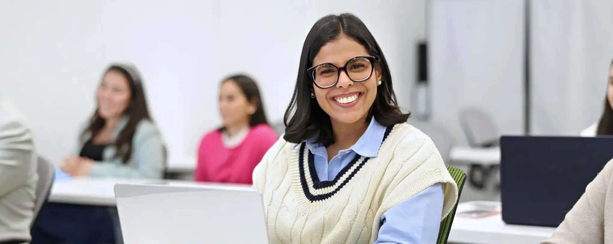 A UNF student looking at the camera and smiling while in the class room