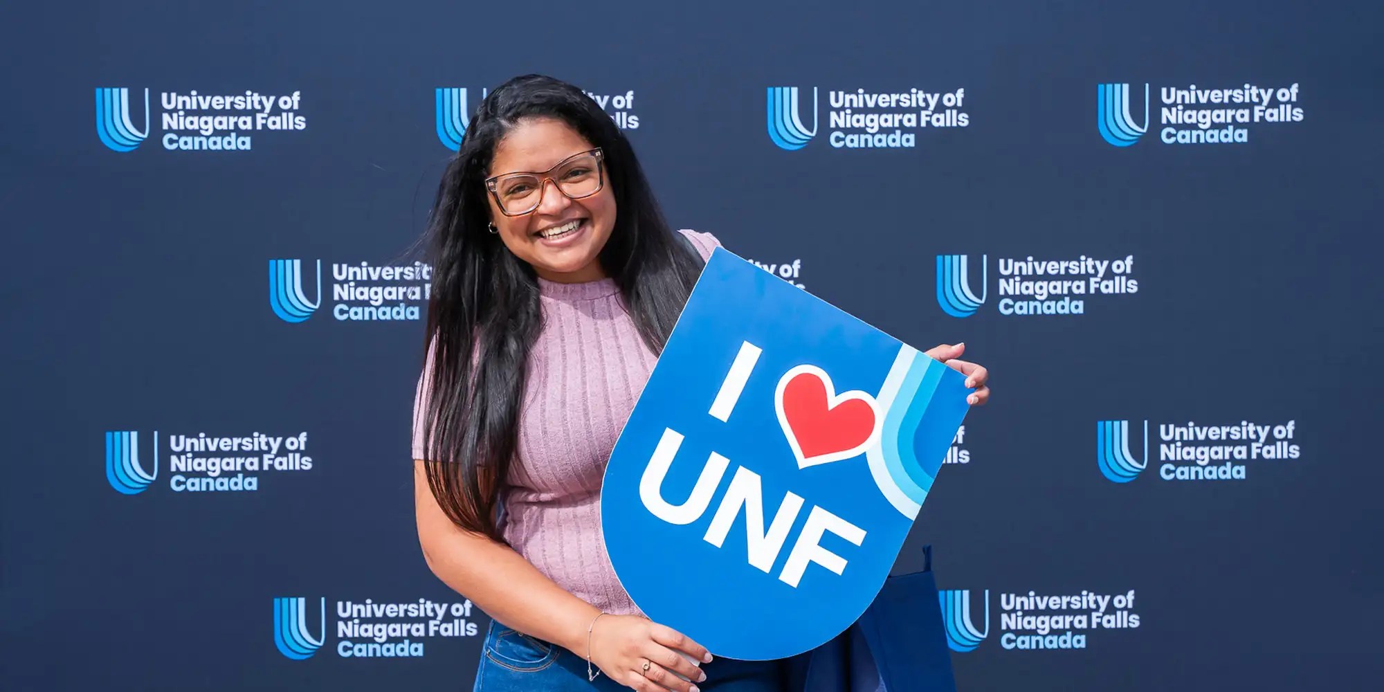 A UNF student holding I love UNF prop