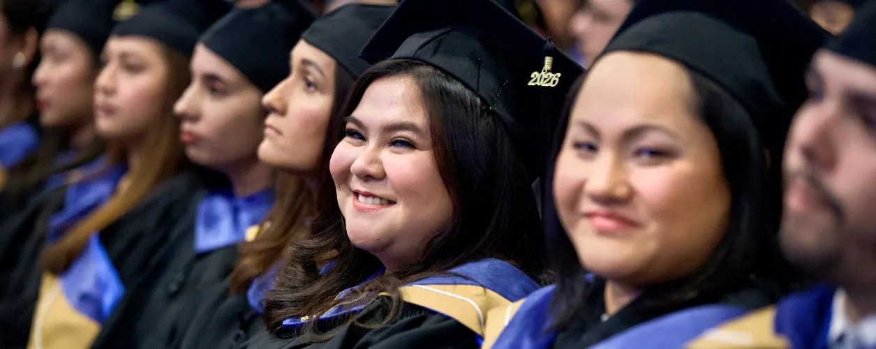 A UNF graduate looking at the camera and smiling